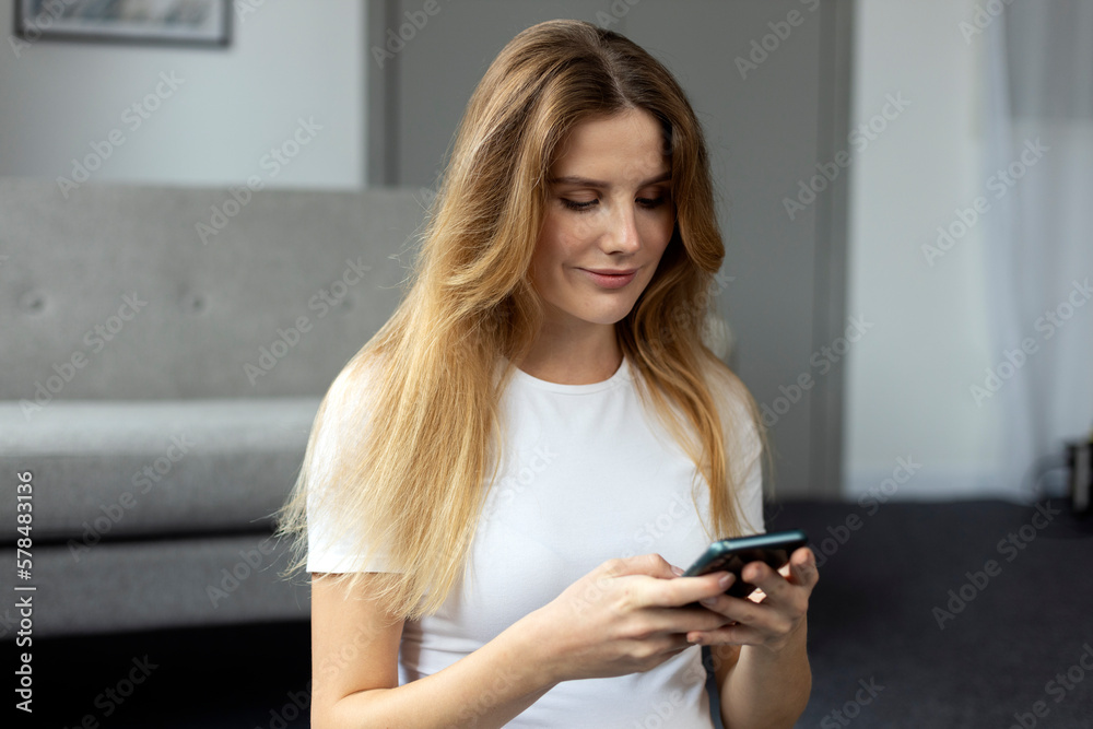 Young beautiful woman holding smartphone using mobile app shopping online, ordering food from home. Attractive female chatting, reading text message. Technology, social media concept Young beautiful woman holding smartphone using mobile app shopping online, ordering food from home. Attractive female chatting, reading text message. Technology, social media concept