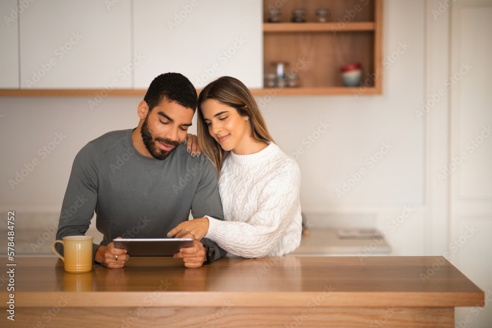 Smiling calm european female hugs millennial arabic man watch video, chatting in social networks Smiling calm european female hugs millennial arabic man watch video, chatting in social networks