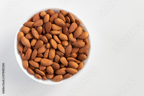 Almond nuts in bowl on white background.