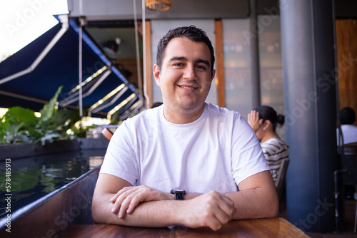 Hombre Latino blanco moreno con una playera blanca en un restaurante disfrutando la vista photo