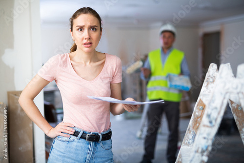 Portrait of confused woman apartment owner holding document. Repair works in apartment.