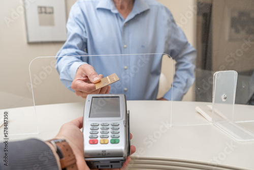 Adult man paying for visit in dentist office in the medical clinic with card