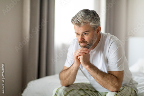 Εκτύπωση καμβά Unhappy middle aged man sitting on bed alone at home