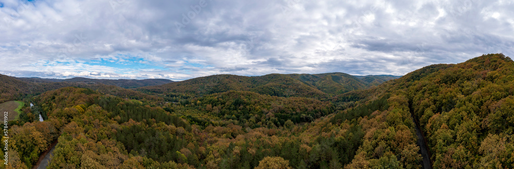 Panoramic Aerial View view of mountain hills. Hilltops covered with autumn forest.