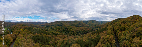 Panoramic Aerial View view of mountain hills. Hilltops covered with autumn forest.