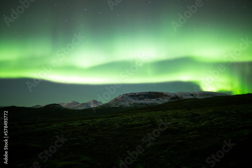 Extremely bright aurora borealis over snowy moutains, Iceland