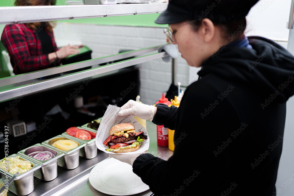 cook prepares vegan burger in her restaurant