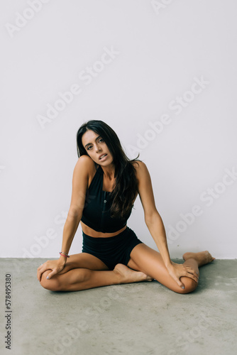 Young beautiful woman with perfect body in underwear sitting on floor posing on white studio background.