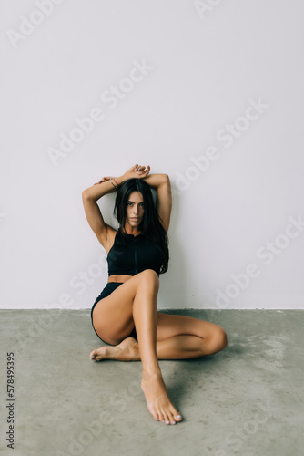 Young beautiful woman with perfect body in underwear sitting on floor posing on white studio background.
