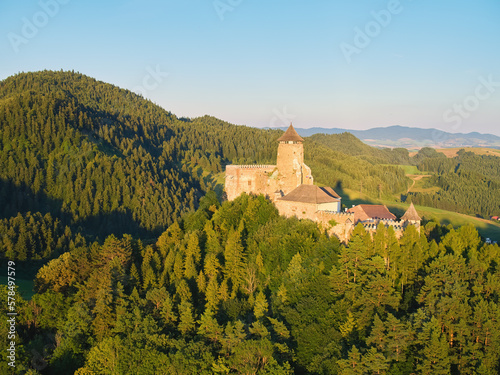 Lubovna Castle, Spis area, Slovakia. Medieval border castle, situated on a rock above wooded hills against blue sky, white clouds, summer. Travelling through the sights and castles of Slovakia. photo