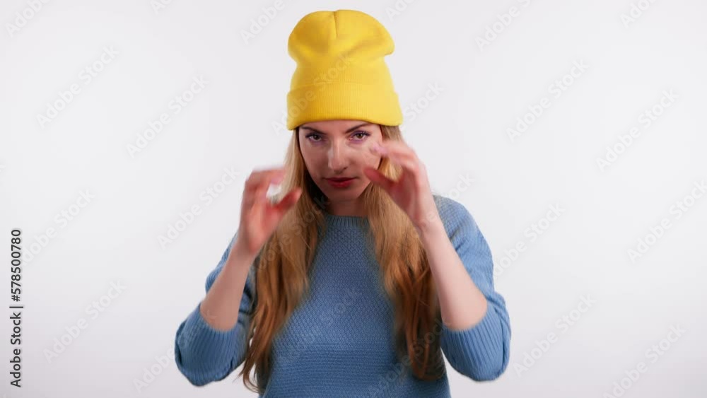Surprised young woman looking through hands binocular gesture, zooming, expressing shock happiness. Wow! Lady in yellow beanie and blue sweater amazed excited. Studio shot isolated on white background Surprised young woman looking through hands binocular gesture, zooming, expressing shock happiness. Wow! Lady in yellow beanie and blue sweater amazed excited. Studio shot isolated on white background