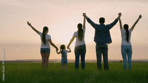 Happy family team holding hands together raise their hands. Teamwork of people. A group of people of different ages at sunset. Partnership and help business concept. Family business.
