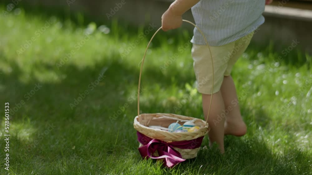 Happy Egg hunt Easter game outdoors. Barefoot child with basket in