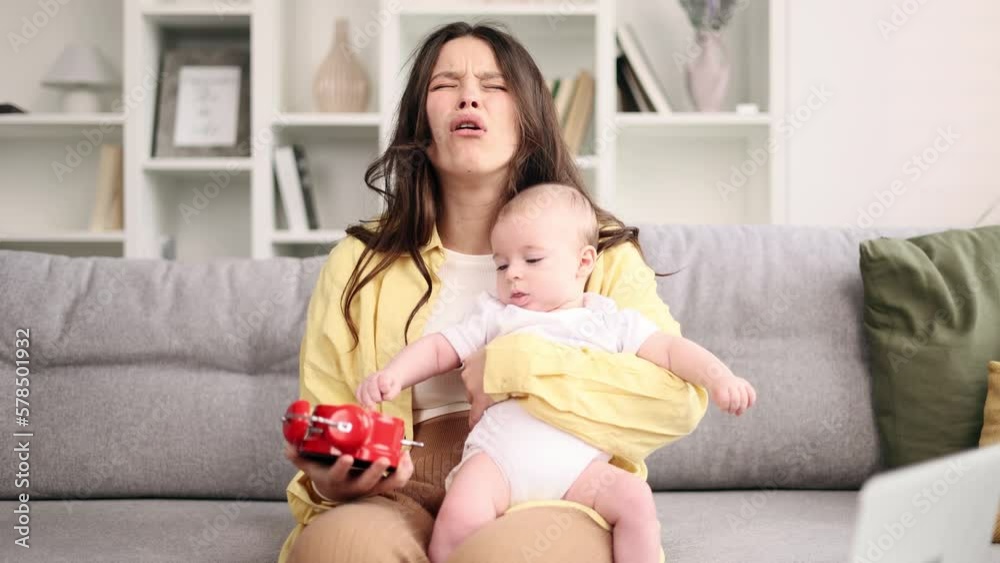 Portrait of tired young woman mother holding child and clock while worries about the lack of time for household chores fatigue due to raising child at home Stress motherhood concept Portrait of tired young woman mother holding child and clock while worries about the lack of time for household chores fatigue due to raising child at home Stress motherhood concept