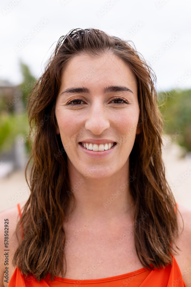 Portrait of happy biracial woman looking at camera and smiling at beach