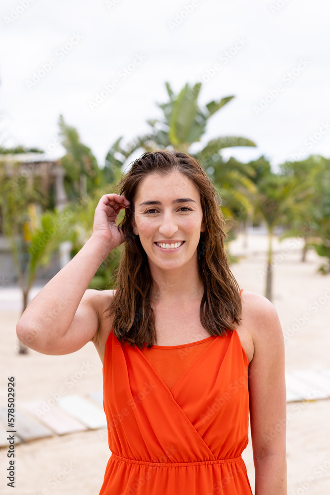Portrait of happy biracial woman looking at camera and smiling at beach, with copy space