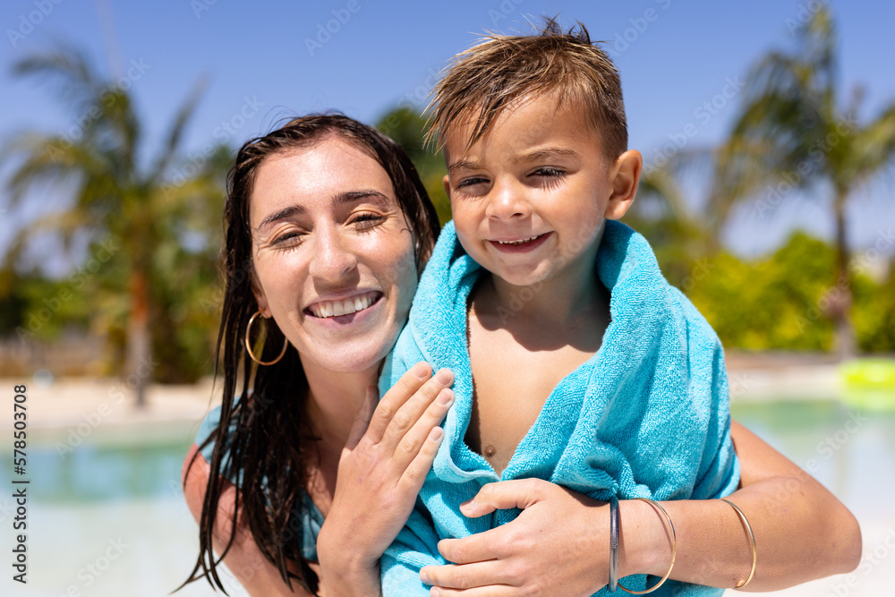 Portrait of happy biracial mother and son smiling by the swimming pool - obrazy, fototapety, plakaty 