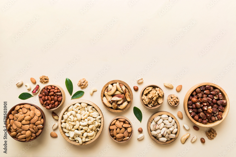 mixed nuts in wooden bowl. Mix of various nuts on colored background. pistachios, cashews, walnuts, hazelnuts, peanuts and brazil nuts