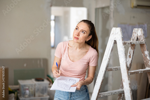 Принти на полотні Focused young adult female design architect holding home plan, planning concept