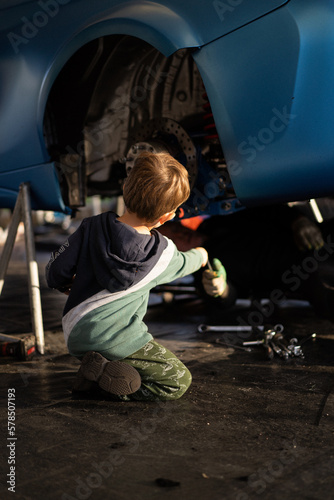 Cuadro en lienzo Little boy helps his dad in the garage to repair the car