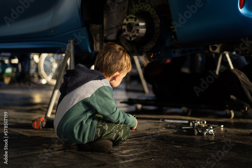 фотографія Little boy helps his dad in the garage to repair the car