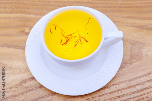 Saffron tea in a white cup on wooden background. A fragrant healthy drink.