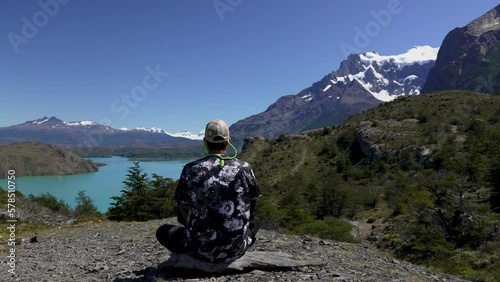 rear view male hiker sitting on a viewpoint contemplating the lake Nordenskjold and mountains in Torres del Paine National Park photo