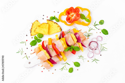 Skewers with pieces of raw meat, red, yellow pepper.Top view.Chicken Skewers breast fillet meat.Uncooked meat skewer.Raw pieces of chicken skewers with pepper onion and pineapple white background. © Nataliia