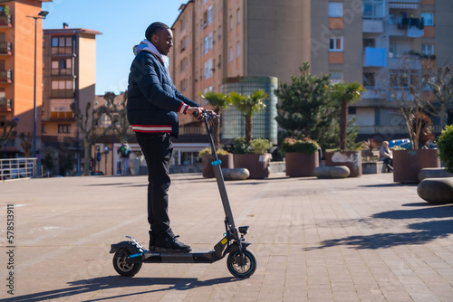 Black ethnic male skateboarding on an electric skateboard, concept of new mobility