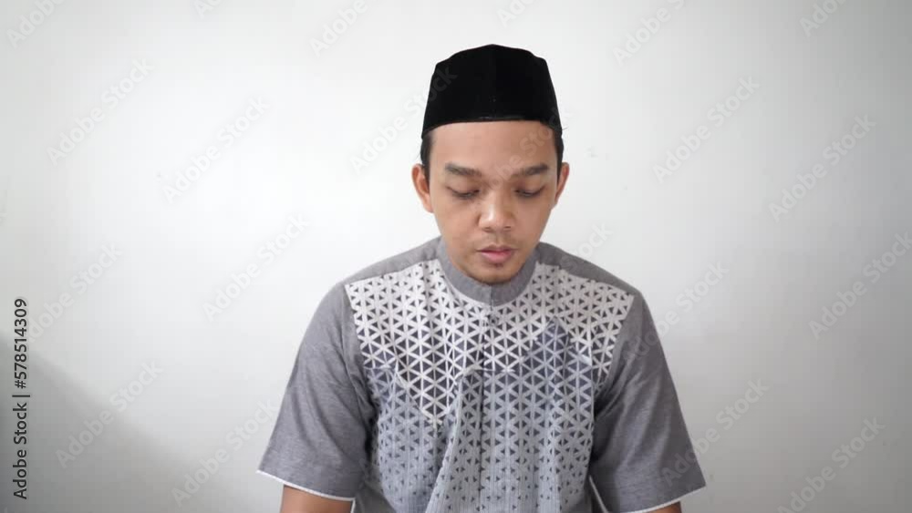 Indonesian Asian muslim man turned his head after salat prayer wears black hat peci or songkok