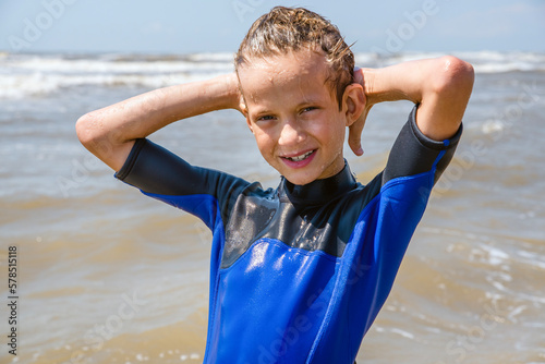 Boy in a wetsuit standing in the water at the beach