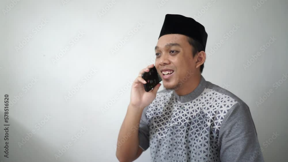 Indonesian Asian muslim man smiling on call wears black hat peci or songkok