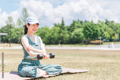 公園でダンベルを使ってワークアウト・トレーニングする女性(筋肉・筋トレ) 