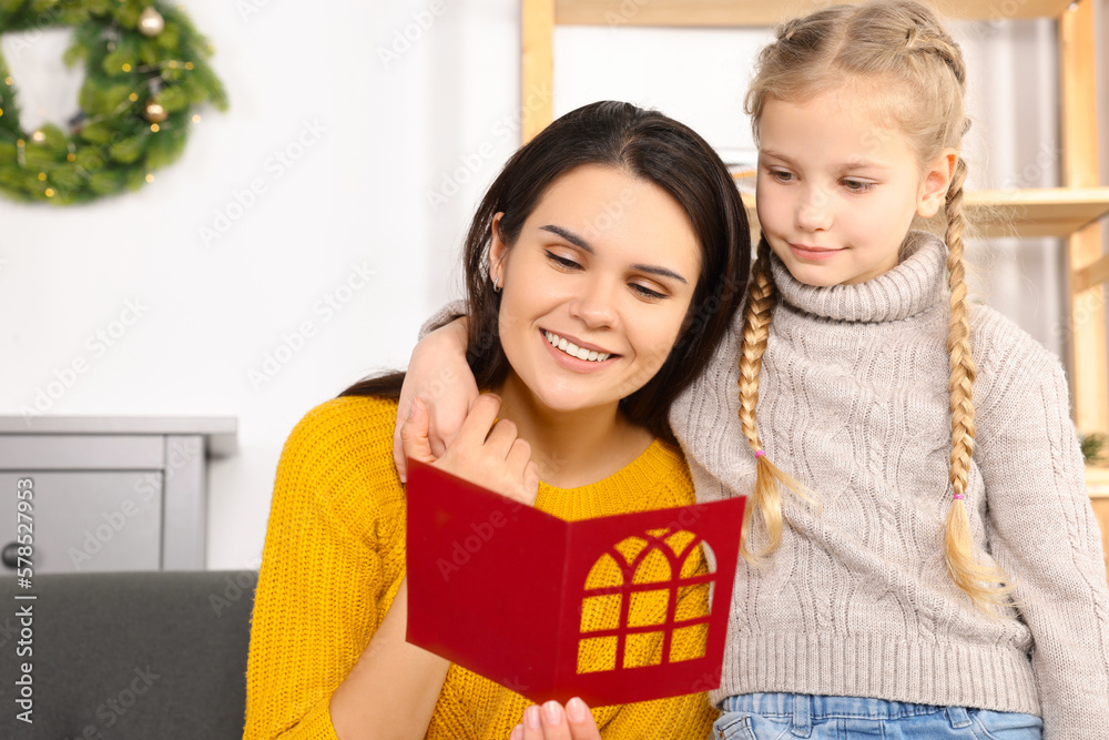 Happy woman receiving greeting card from her daughter at home