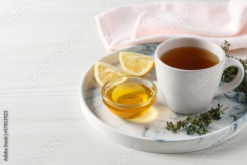 Aromatic herbal tea with thyme, honey and lemons on white wooden table, space for text