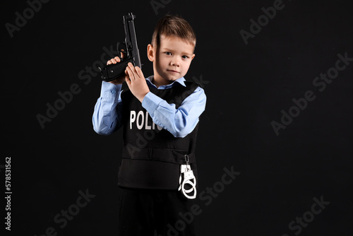 Cute little police officer with gun on black background