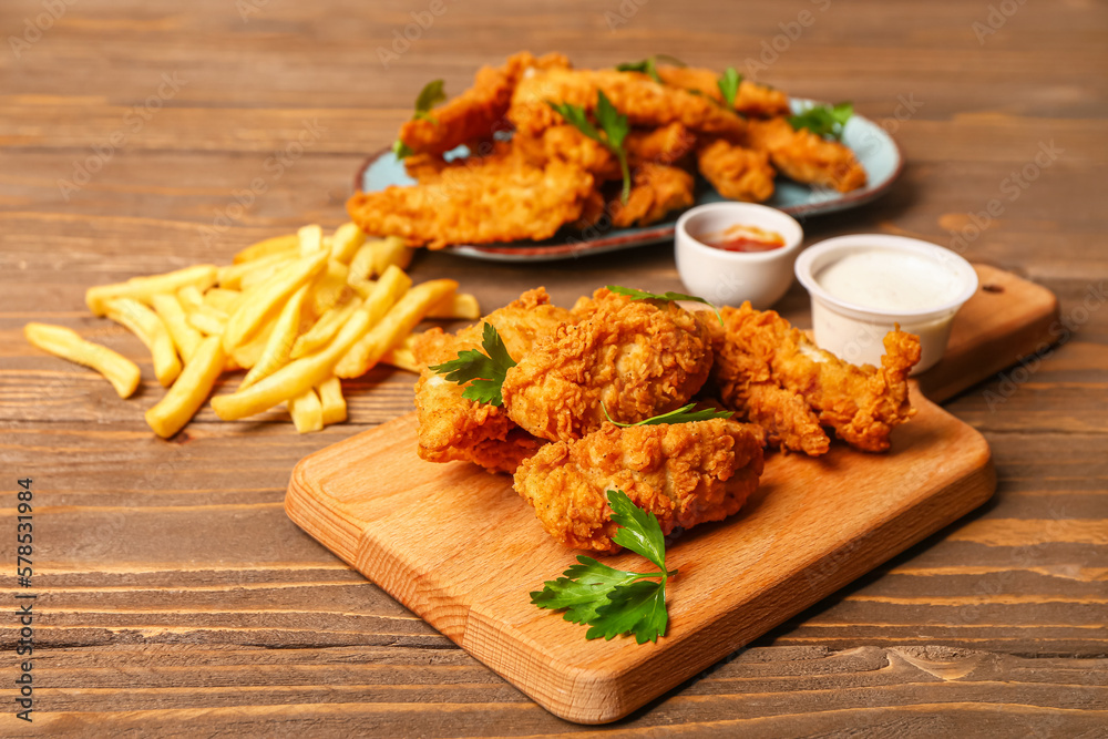 Board with tasty nuggets, sauces and french fries on wooden background Board with tasty nuggets, sauces and french fries on wooden background