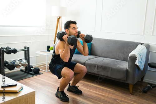 Tableau sur toile Sporty man using weights during his home workout