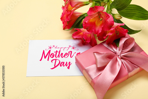 Card with text MOTHER'S DAY, gift box and alstroemeria flowers on color background © Pixel-Shot
