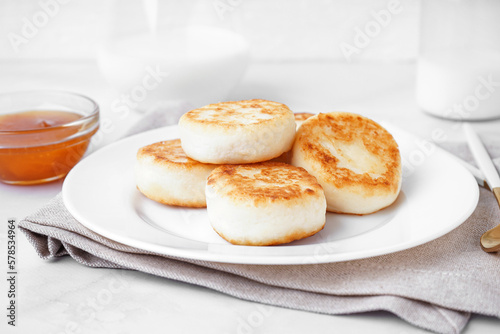 Plate of tasty cottage cheese pancakes with jam on light background, closeup