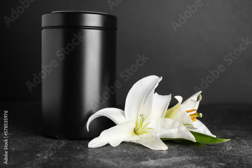 Mortuary urn and white lily flowers on dark background