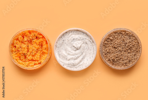 Jars of natural body scrub on color background