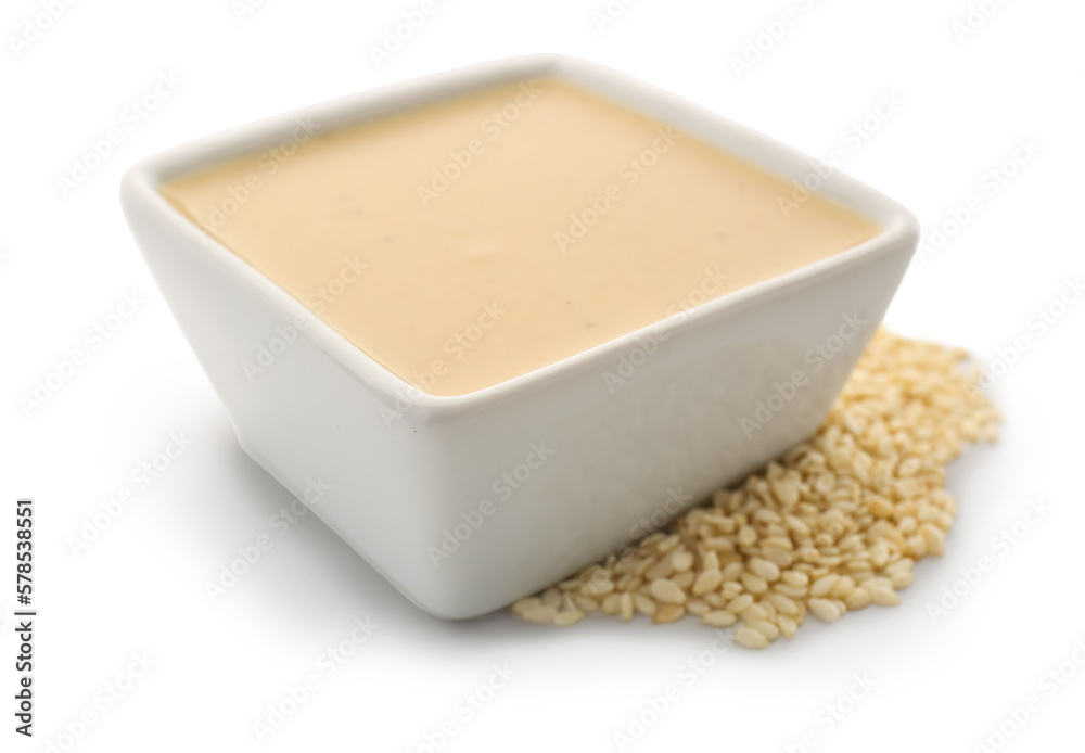 Ceramic bowl of tasty tahini and sesame seeds on white background Ceramic bowl of tasty tahini and sesame seeds on white background