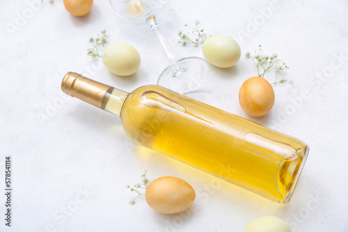 Composition with bottle of wine  glass  Easter eggs and gypsophila flowers on light background