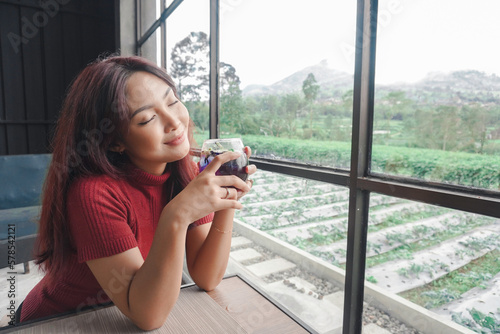 Portrait of joyful young woman enjoying a cup of tea at home. Smiling pretty girl drinking telang tea in rainy season. Free Download Portrait of joyful young woman enjoying a cup of tea at home. Smiling pretty girl drinking telang tea in rainy season. - GFXLoad