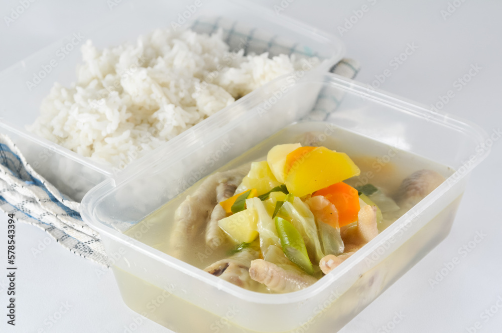 soup with chicken legs served in a transparent plastic container and