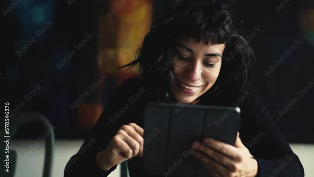 Happy Hispanic woman using tablet device browsing internet online