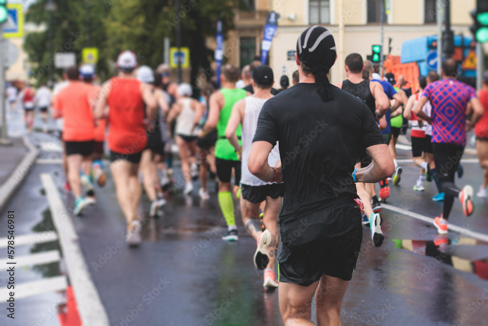 Fototapeta premium Marathon runners crowd, participants start running the half-marathon in the city streets, crowd of joggers in motion, group athletes outdoor training competition in the rain