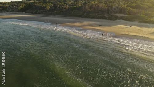 Circular drone flight over Playa Grande Beach in Uruguay where Kids play in the waves at sunset photo