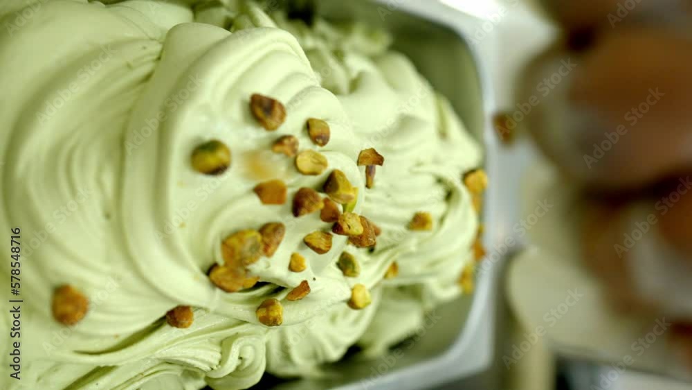 factory worker putting chunk of pistachio into a tray of pistachio ice cream